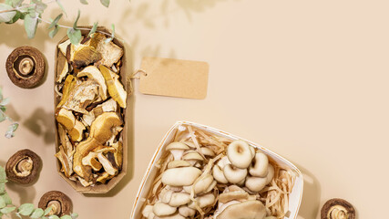 Mushrooms. Sustainable sale of organic dry and natural mushrooms in eco packages with empty label on beige background with green leaves. Healthy food. Flat lay, copy space