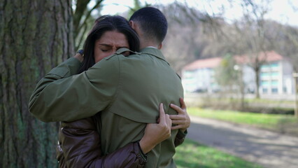 Fototapeta premium Compassionate embrace between a suffering couple. Empathic moment between two people hugging each other durring difficult times standing outside at park. Support concept