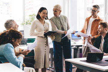 Diverse financial experts with paperwork communicate about business planning during working day in...