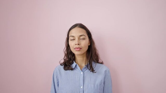Young beautiful hispanic woman saying yes with head looking surprise over isolated pink background