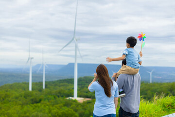 Progressive happy family enjoying their time at wind farm for green energy production concept. Wind...