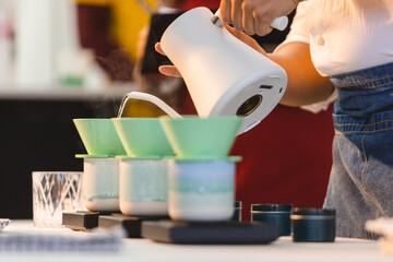 Pouring water over into a coffee pot.