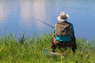aged man fishing on the shore of the lake in the summer - 600523854