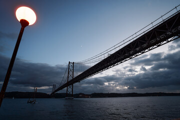 Beautiful landscape with suspension 25 April bridge bridge over the Tagus river in Lisbon at night time, Portugal.