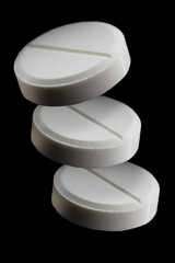 Pharmacy healthcare and drug concept. Close up of three white pills hanging in the air on black background.