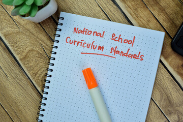 Concept of National School Curriculum Standards write on book isolated on Wooden Table.