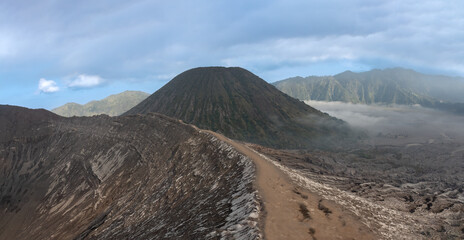 Hiking trail along the edge of Mount Bromo's crater with Mount Semeru, Mount Batok and the Sea of Sand (Segara Wedi) in the background, East, Java, Indonesia © Luis