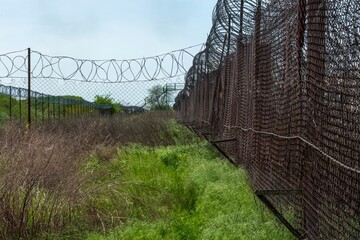 Green grassed outer fence of an abandoned old criminal prison on a sunny day