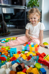 Little girl play with constructor toy on floor in home, educational game, spending leisure activities time concept