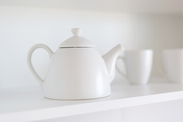 white teapot and cups on the shelf