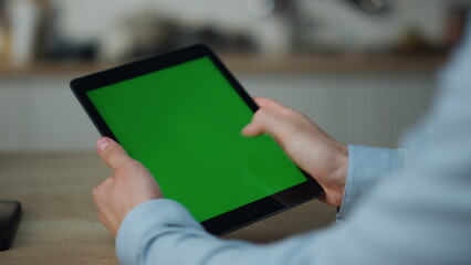 Hands touching greenscreen tablet searching information sitting at table closeup