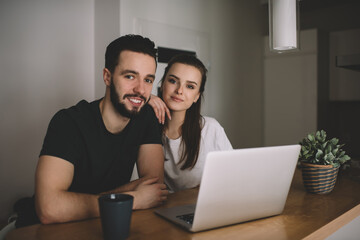 Happy young couple using laptop in cafe