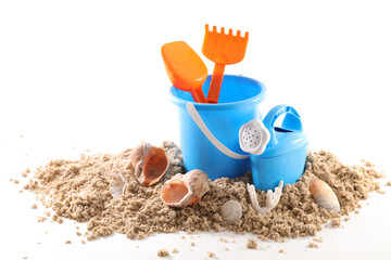 Toy bucket and shovel with sand and seashells isolated on white background - obrazy, fototapety, plakaty
