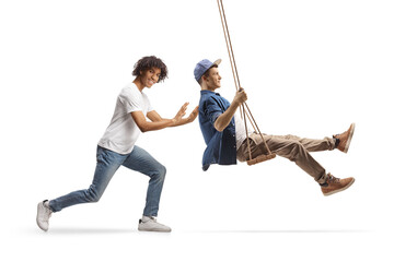 Young african american man pushing a caucasian guy on a swing