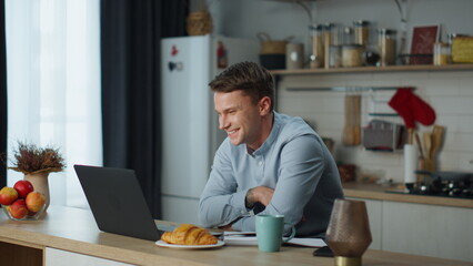Fototapeta premium Guy speaking video call with girlfriend sitting at kitchen. Man using web chat.