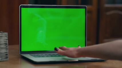 Woman hand turn on green mock-up screen on modern laptop indoor close up. 