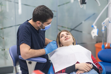 Fototapeta na wymiar Happy female patient looking at dentist in medical mask smiling experienced doctor in rubber gloves preparing woman for teeth treatment in dentistry clinic