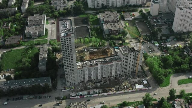 Residential complex under construction in city in summer. Stock footage. Districts of city with green courtyards and residential buildings. Construction of residential complex in city with green