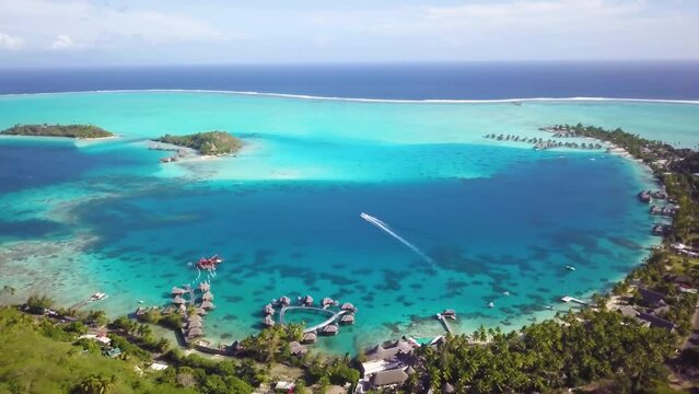 4K Aerial Drone footage of green hills, nature, turquoise beach, water villa bungalows, cruising boat and blue lagoon in Bora Bora, Tahiti, French Polynesia. Luxury, romantic, honeymoon destination.