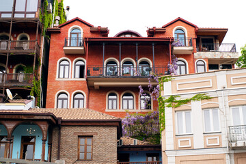 Fototapeta premium Beautiful old Georgian houses in Tbilisi overgrown with bright wisteria flowers on the streets of the city in spring