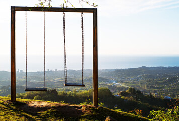 Landscape with a lonely swing on a hill in the mountains overlooking a mountain village, sea, sky...