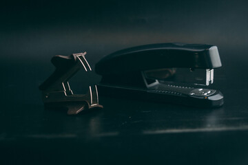 anti -stepler with stapler lie on a black background , stationery