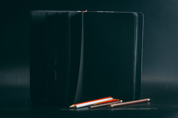 black drawing pad with pencils on a black background