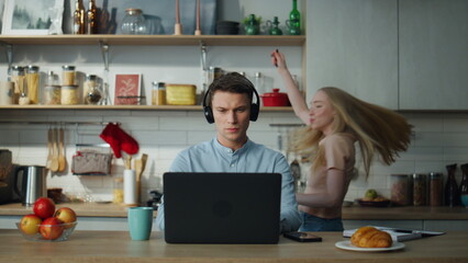Fototapeta na wymiar Man listening online course headphones sitting at kitchen table drinking coffee.