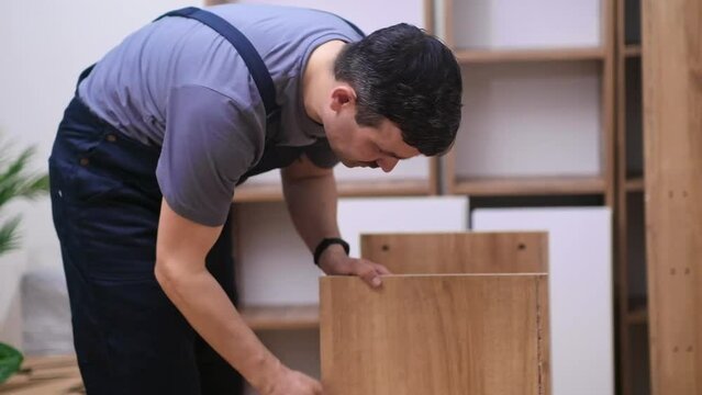 Custom furniture delivery and installation concentrated handyman checking planks made of quality hardwood ready to assemble rack for office interior carpentry industry