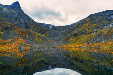 Fototapeta na wymiar Great little mirror lake and trees in autumn setting with Krokelvtinden mountain in the background, Troms og Finnmark, in northern Norway