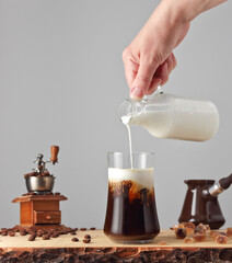 ice coffee with cream with manual coffee grinder and coffee pot on a light background