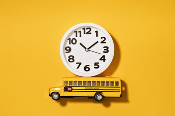 School bus with white clock on top on yellow back ground. Back to school. Delivery service and...
