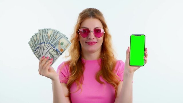 Green screen, chroma key, dollars, money cash and woman with phone for product placement, branding and mobile app marketing. Smiling lady female with mobile smartphone in studio isolated on white
