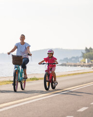 Fototapeta premium Mother and daughter with bike on the coast