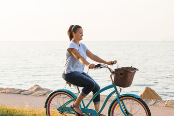 Happy smiling woman riding bicycle along the coast at summer © 24K-Production