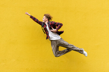 young guy student with backpack flies forward and hurries to study, man in superman pose jumps and...
