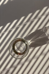 Glass of water on the white table with shadows from the morning light throught the blinds