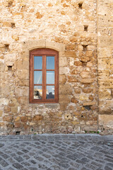 Window in an old yellow stone facade in Greece
