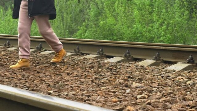 A girl crosses the railway in a dangerous place