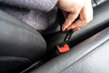 Women's hand fastening the seat belt of the car