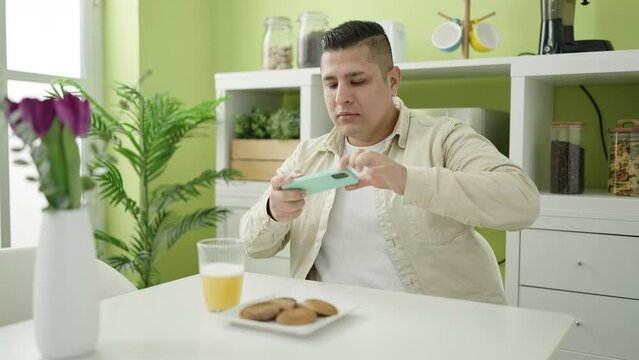 Young hispanic man make photo by smartphone to breakfast at dinning room