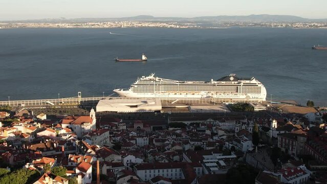 Aerial view of the Alfama cityscape and approaching a large cruise ship at the Lisbon cruise terminal, in Portugal