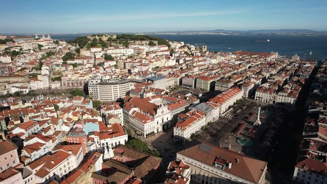 Aerial drone reveal of Baixa District in Lisbon, Portugal with major landmarks visible including Rossio Square and St. George Castle