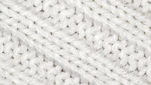 Fabric knitted with white yarn threads, rotating, turning, close-up, macro
