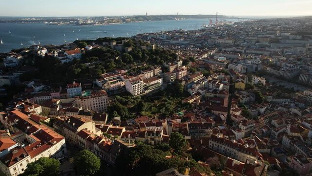 Aerial drone backwards reveal of Miradoura da Graca major Lisbon, Portugal landmarks visible including St. George Castle and 25 April Bridge