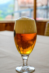 Fresh draught lager or IPA beer is glass served in indoor cafe close up, glass of beer