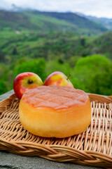 Spanish hard smoked cow cheese from Pria, Asturias, served outdoor with apples and view on green slopes of Picos de Europa mountains