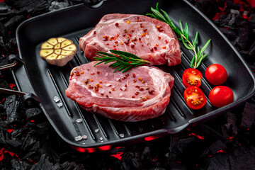 Raw steak with vegetables and herbs on a grill pan. Organic meat