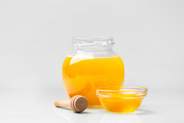 Honey in a jar with a wooden dipper on a white isolated background.