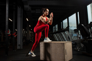 athletic woman in red sportswear training in black gym, slim girl jumping in fitness hall, attractive woman on crossfit